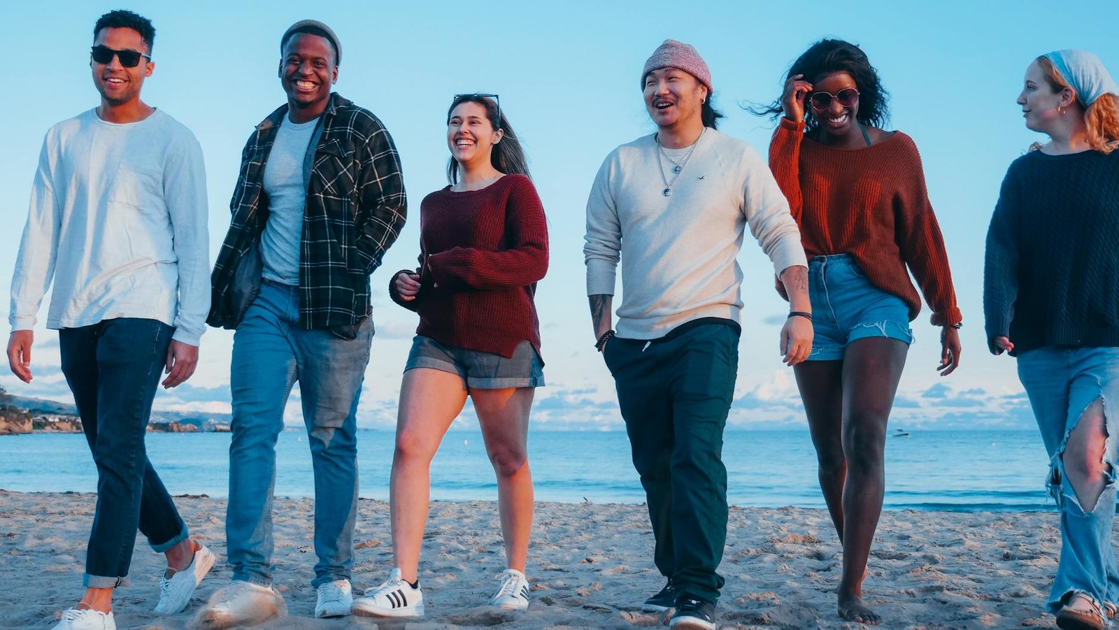 group of friends walking on beach shore